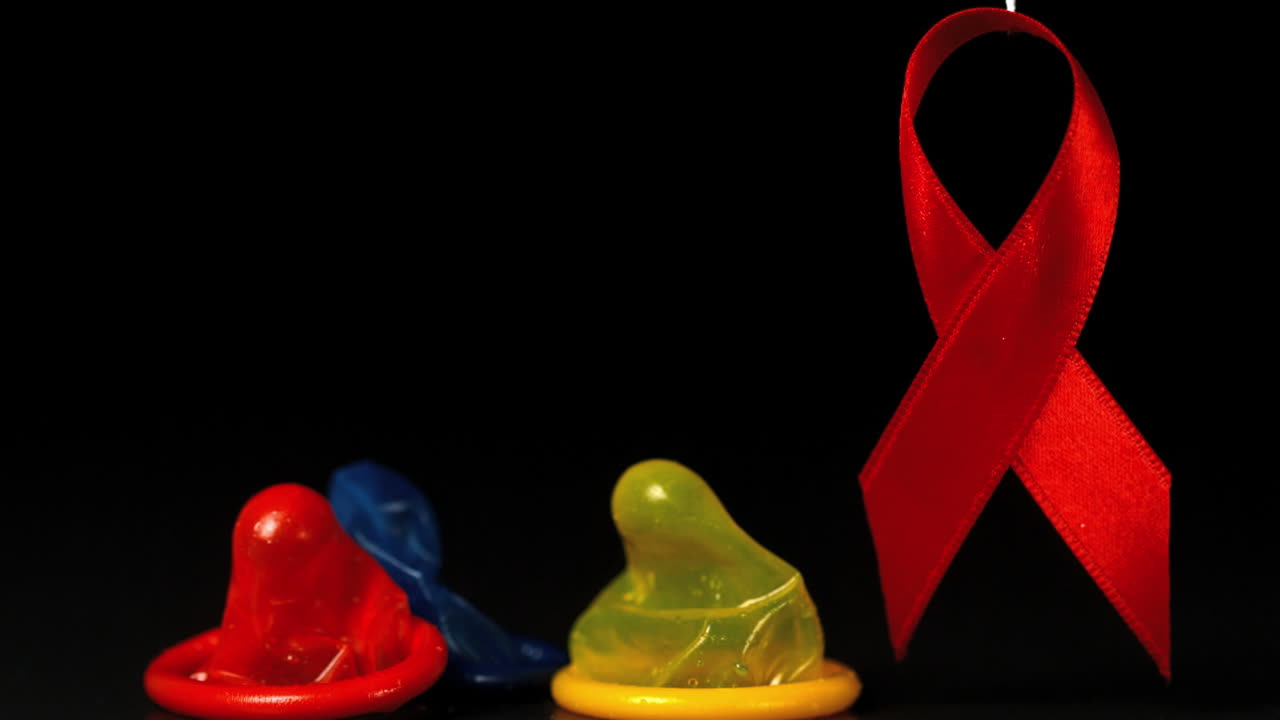 Coloured condoms dropping down beside red ribbon 