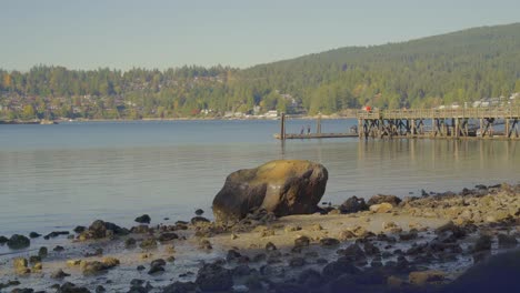 giant rock on shoreline surrounded by scattered rocks surrounded by water