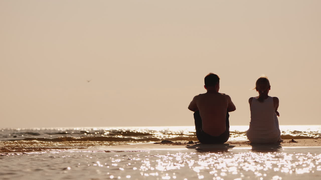 남자와 여자가 해변에 나란히 앉아 있다