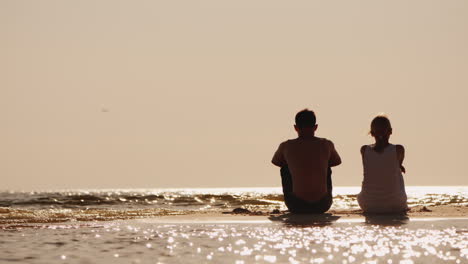 a man and a woman sit side by side on the beach