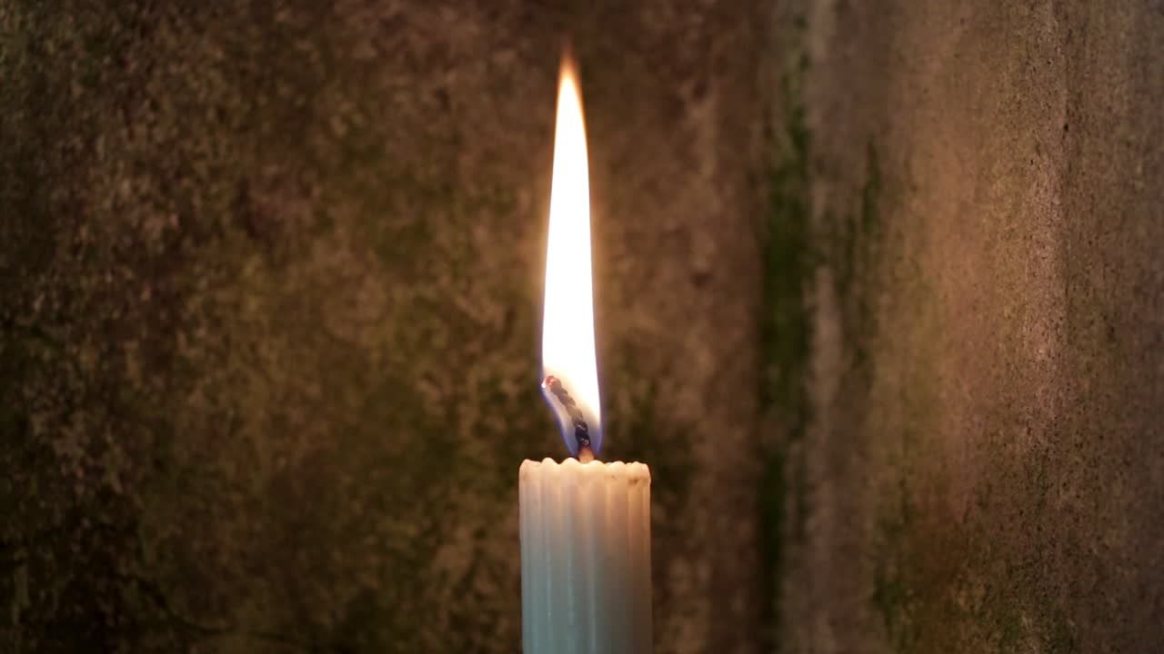 Candle burning with old church wall as background setting