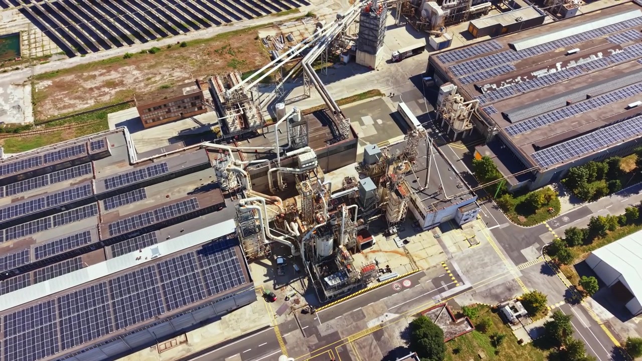 Local industrial com painéis solares e maquinário durante o dia em uma área de fabricação
