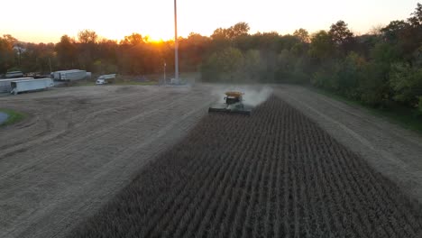 combine harvests soybean crop at sunset