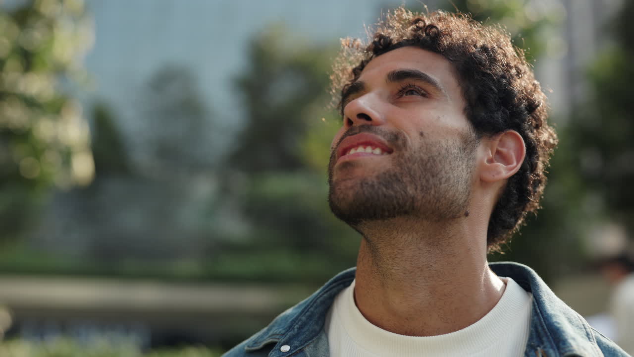 Hopeful Young Man Looking Up with a Smile Outdoors