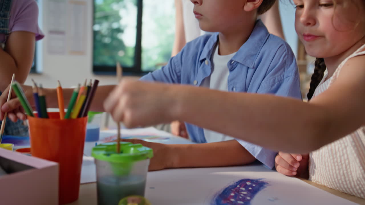 Elementary schoolchildren painting artclass closeup. Woman teacher guiding group