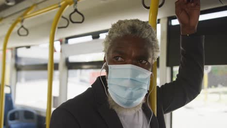 african american senior man wearing face mask travelling in the bus