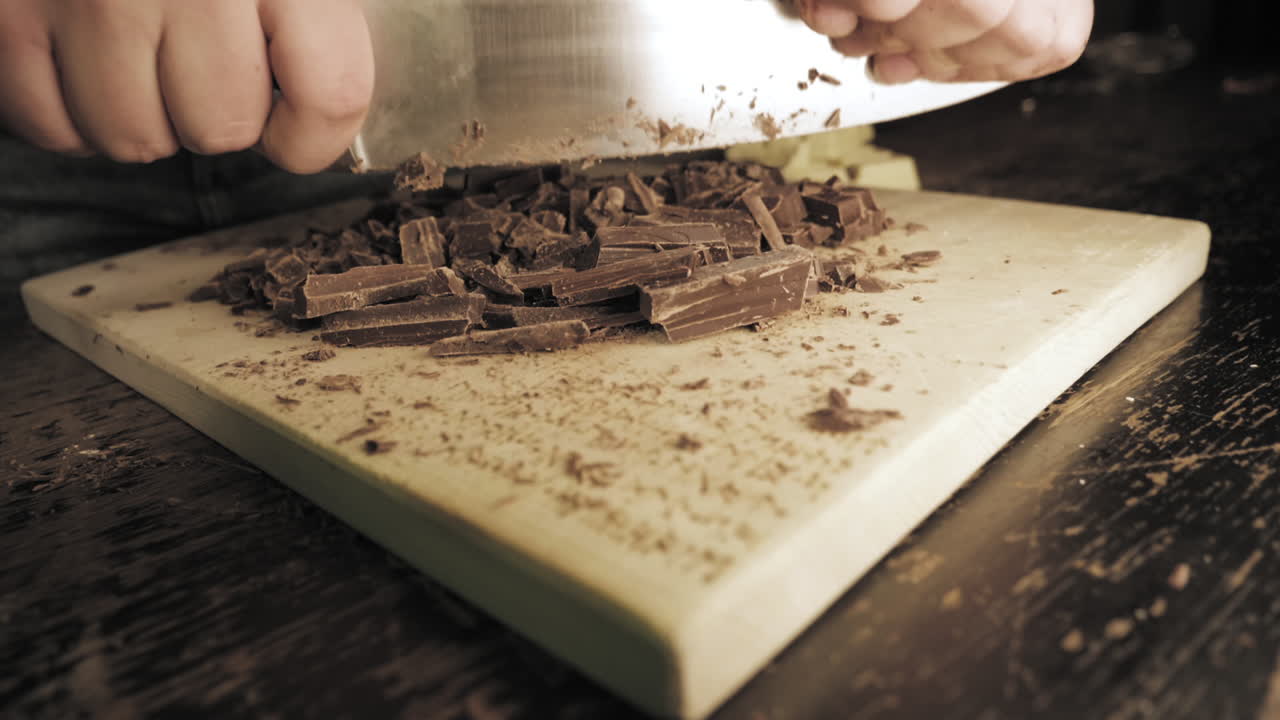 Slow Motion of female hands preparing chocolate cookies, cutting up dark chocolate.