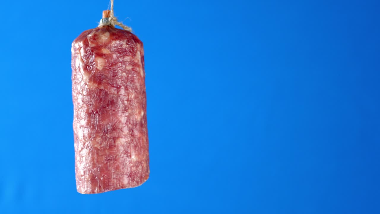 Half stick of salami hanging from a rope.