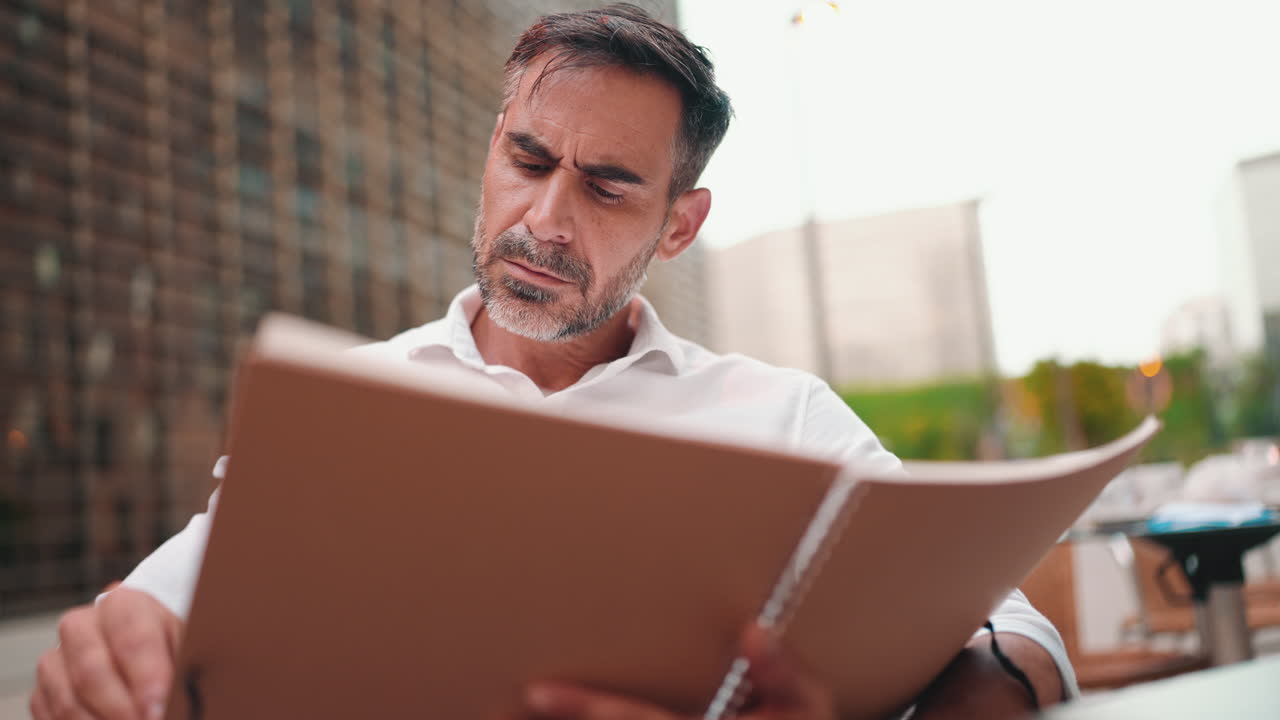 Man reading a menu at an outdoor cafe