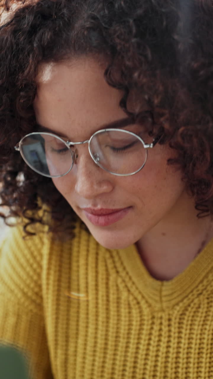 Joven con pelo rizado y gafas trabajando y sonriendo.