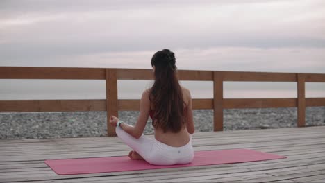 woman meditating on a beach yoga mat