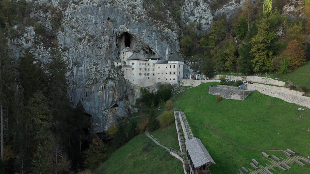 toma aérea en cámara lenta con movimiento hacia adelante en el castillo de predjama al atardecer
