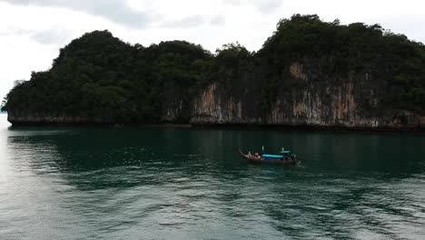 imágenes de drones de un bote de cola larga navegando alrededor de las islas de krabi, tailandia, con las formaciones rocosas de piedra caliza que sobresalen del agua y el océano en el fondo