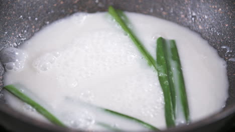 cooking sweet coconut milk with pandan leaves for mango sticky rice, sweet thai desert flavoring