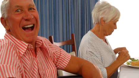 retrato de un hombre mayor feliz sentado en la mesa de comidas