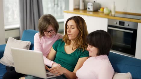 Glückliche-Familie-Mit-Zwei-Töchtern-Mit-Down-Syndrom,-Die-Auf-Dem-Sofa-Sitzen-Und-Spaß-Am-Laptop-Haben