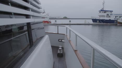 walking on side of boat with chrome railing looking at other boats in harbor