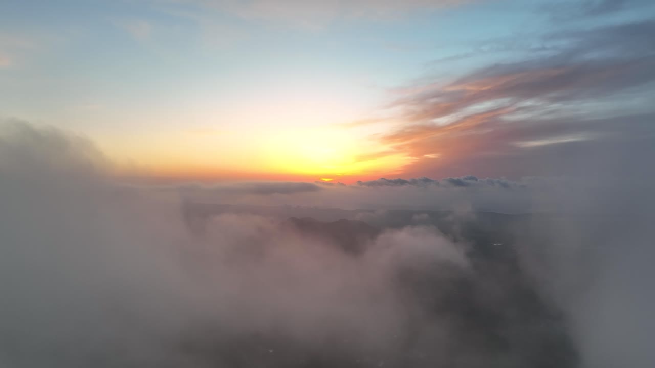 volando hacia el amanecer sobre un valle verde con nubes