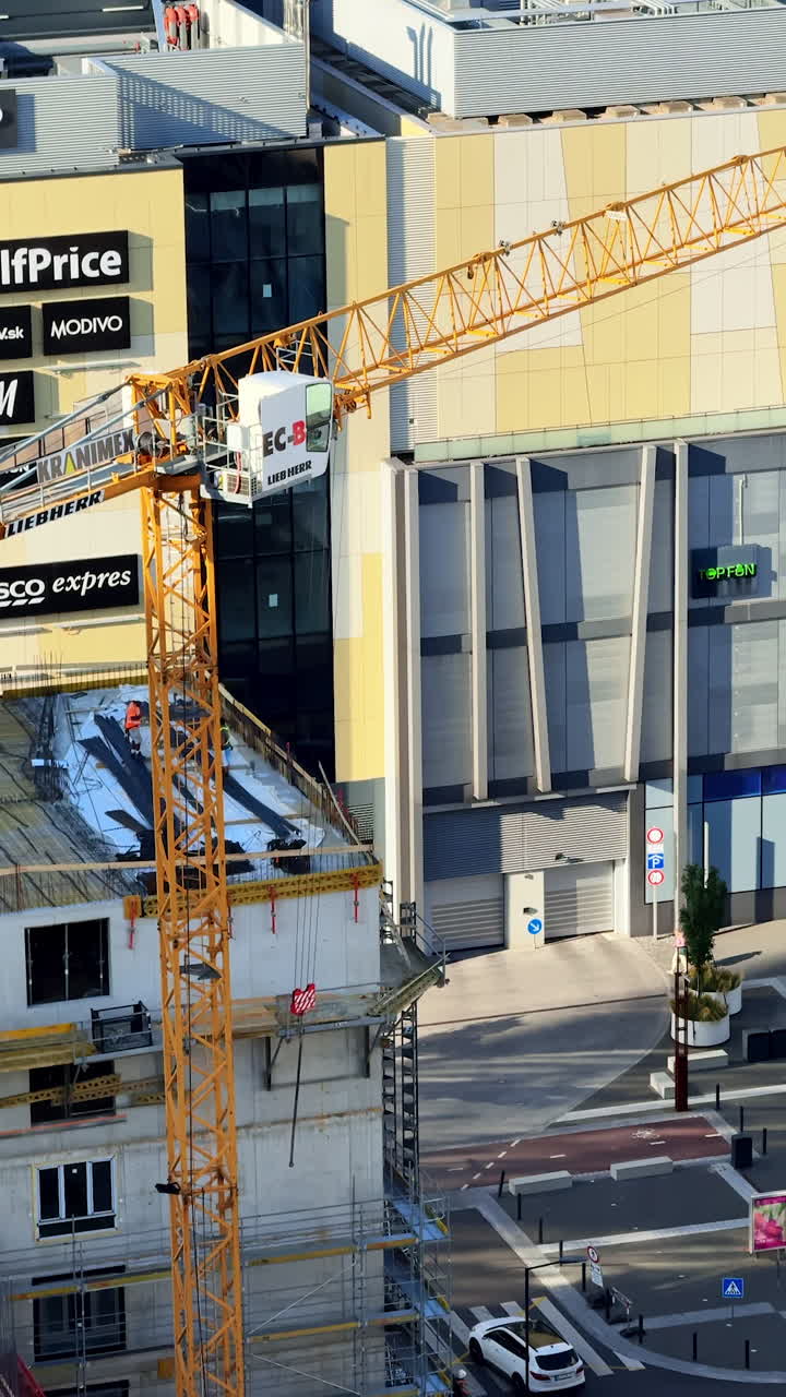 Construction near shopping center. A crane towers over a construction site beside a modern shopping center, capturing busy urban development vibes