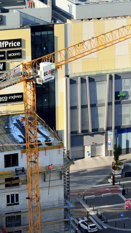 construction near shopping center. a crane towers over a construction site beside a modern shopping center, capturing busy urban development vibes