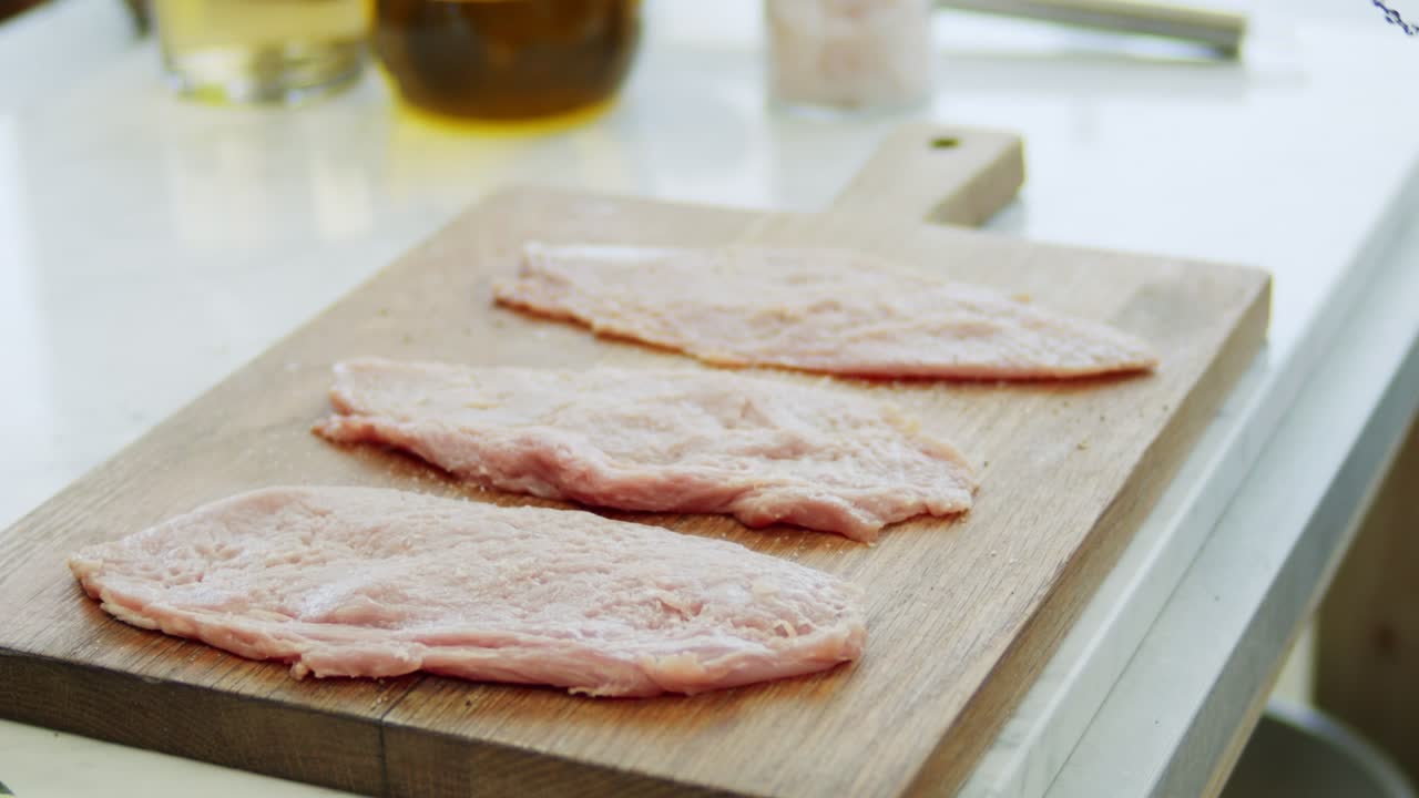 Donna che aggiunge pepe a una cotoletta di vitello cruda su un tagliere