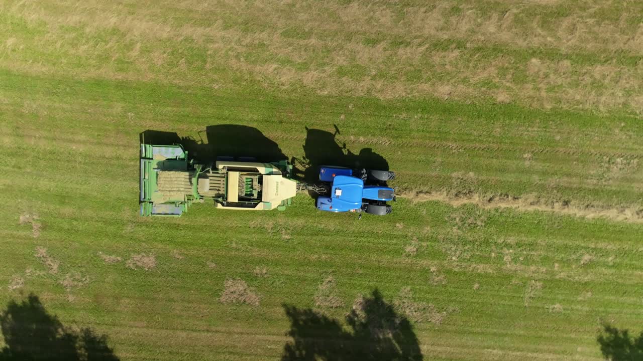 Tractor makes bales of drying grass in a meadow. Drone view from a bird's eye view. Harvesting in summer in the Czech Republic