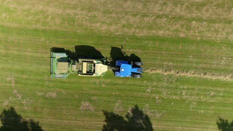 tractor makes bales of drying grass in a meadow. drone view from a bird's eye view. harvesting in summer in the czech republic