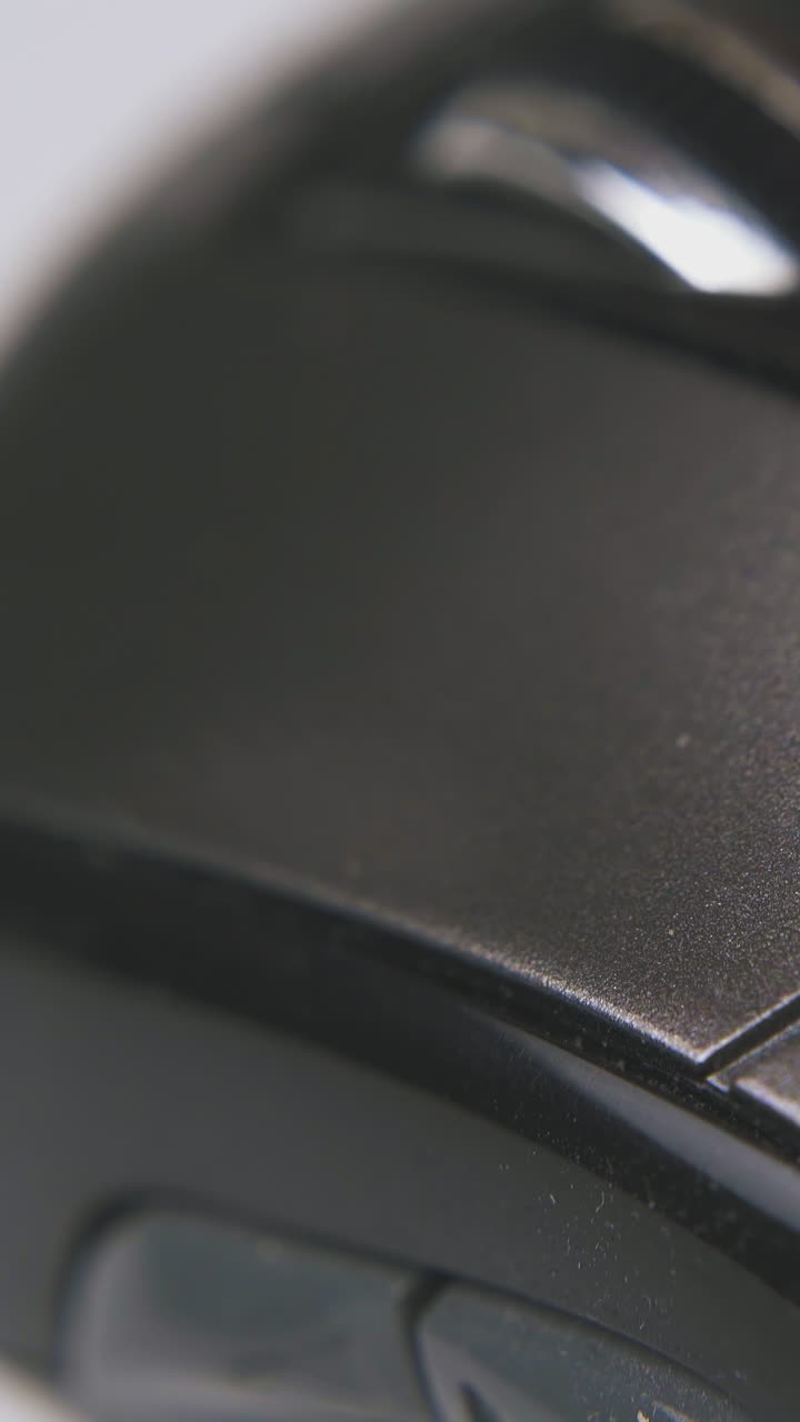 man presses button and shakes modern black computer mouse to work on white surface extreme close view
