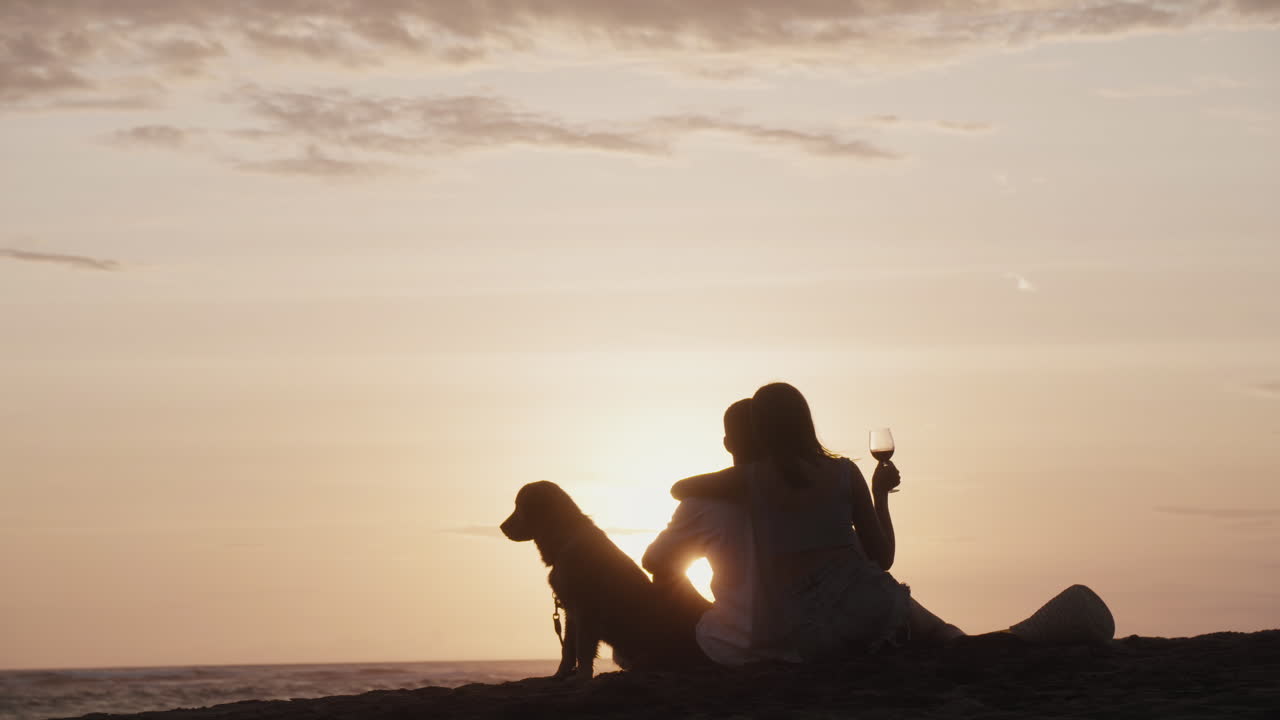 해가 지는 모래 위에 앉아 있는 커플