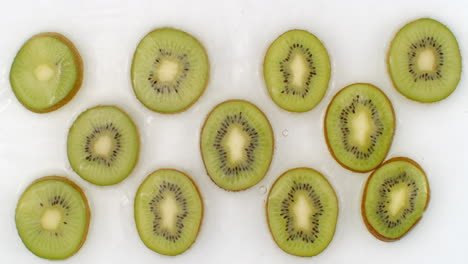 in slow motion water splashes pour water onto a beautiful juicy citrus fruit a lot of kiwi on a white background