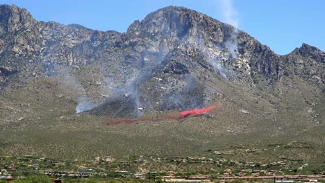 aerial firefighting, aircraft dropping chemical retardant under wildfire on hill of santa catalina mountains, arizona usa