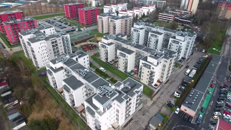 secure, modern residential complex with white and red buildings in the city center, featuring parking lots and a playground