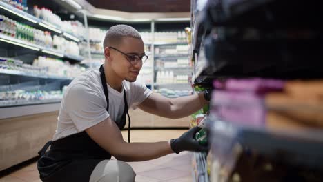 handsome worker in glasses rearranging goods on the shelves