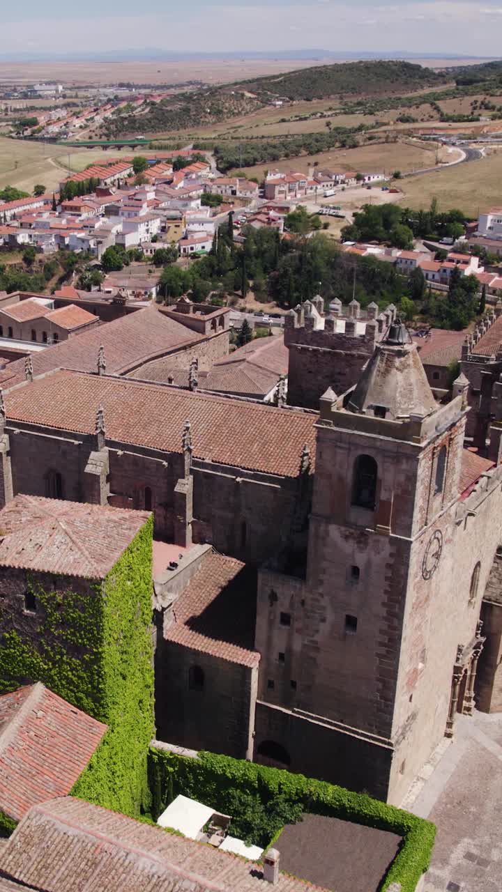 Vista aérea vertical da Igreja de San Mateo em Cáceres, Espanha, destacando sua arquitetura histórica e a paisagem urbana ao redor.