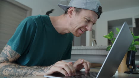 male freelancer with tattoo on right arm kneeling over keyboard with baffled look to camera