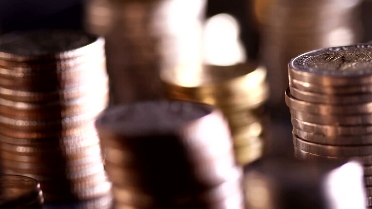 Primo piano di monete impilate sul pavimento in penombra, concetto di sfondo aziendale e finanziario per il risparmio o l'investimento, con messa a fuoco ravvicinata e profondità di campo ridotta.