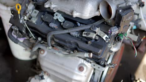 Big-block-engine-V8-or-V6-4-cylinder-sitting-on-concrete-ground-floor-in-mechanics-garage-shop-having-just-been-removed,-as-camera-slow-pans-up