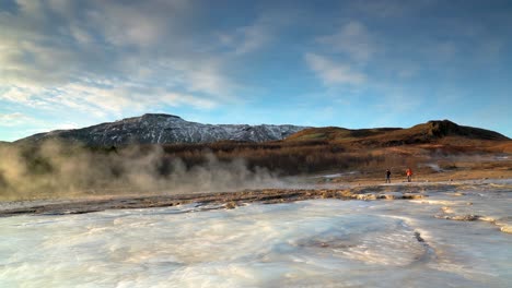 two people waiting for strokkur eruption in geothermal area in haukadalsvegur, iceland