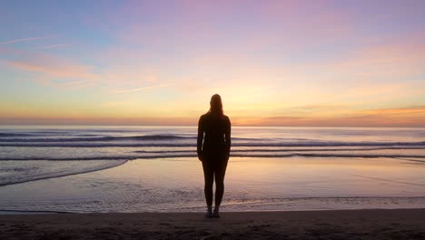 Silhouette-Einer-Frau,-Die-Ihre-Arme-Ausbreitet-Und-Das-Meer-Bei-Sonnenaufgang-Beobachtet