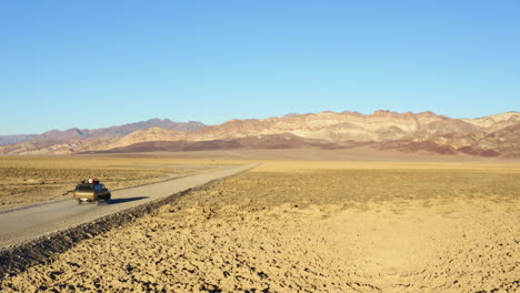 follow through shot of suv on road amidst hot dry barren terrain of death valley national park