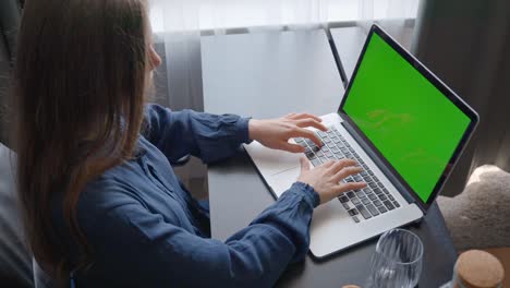 primer plano de una mujer en la oficina escribiendo en una computadora portátil con pantalla verde