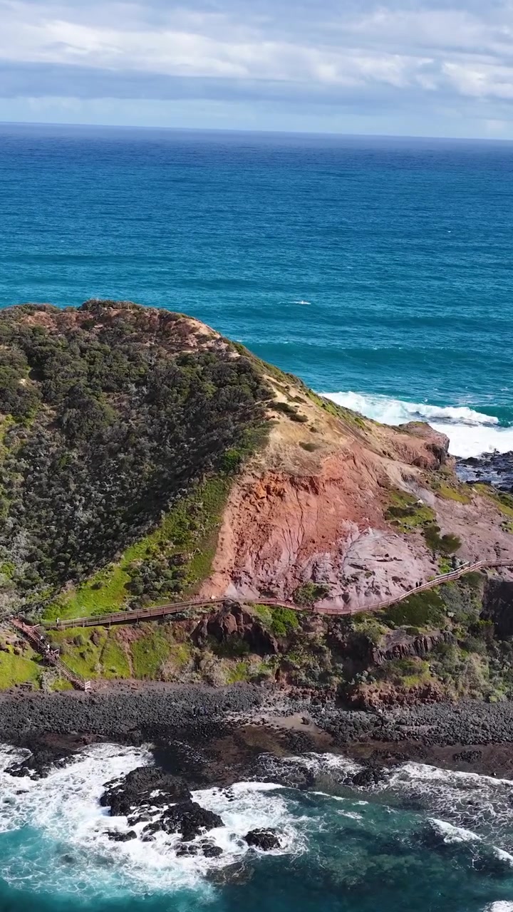 Telecamera drone scivola sopra scogliere aspre, oceano blu e costa rocciosa sotto la luce del giorno intensa