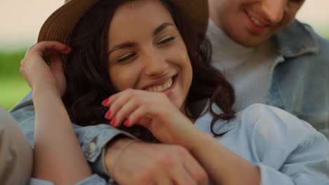 cute couple spending time on picnic in park. man touching woman hair outdoors