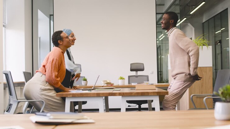 An Woman And A Muslim Woman Co Workers Interview A Young Man Sitting At A Table In The Office 12