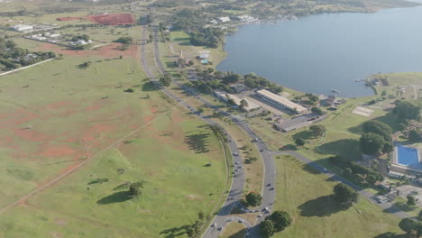 Sobrevuelo-Aéreo-Lento-De-La-Carretera-Junto-Al-Lago-En-Brasilia,-Brasil-A-La-Luz-De-La-Mañana