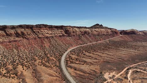 aerial view of highway 95 running through northern comb ridge in southeastern utah, blue sky, early spring, red cliffs