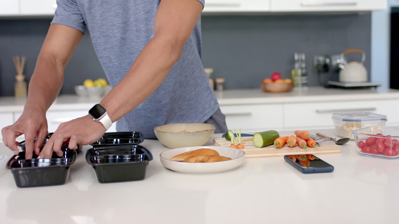 Männerhände beginnen, Gurken und Karotten auf der Arbeitsplatte zu schneiden und vier Essensboxen für das Mittagessen zu füllen.