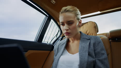 Focused-business-woman-working-laptop-computer-at-luxury-car.