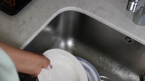 woman washing dishes in kitchen sink