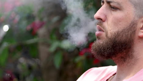 primer plano de un hombre caucásico barbudo fumando cigarrillo electrónico